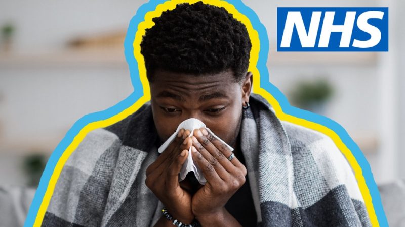 Man smothered in blanket, sneezing into a tissue