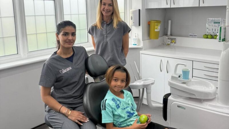 Dentist, receptionist and a child patient in dental surgery to promote dental access project