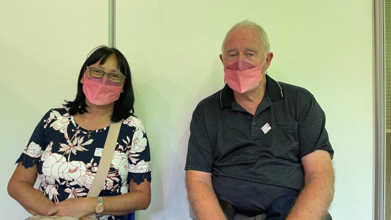 A woman and a man wearing face masks waiting at a vaccination clinic in Croydon